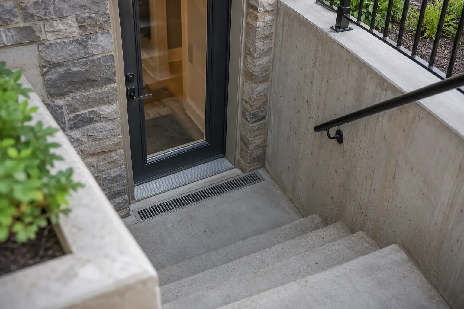 Below-grade landing with trench drain and waterproof door threshold.