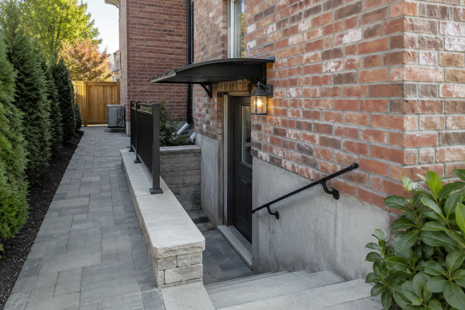 At-grade side basement entrance with canopy, light and paved walkway.